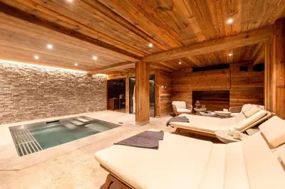 a room with a swimming pool with chairs at Chalet Les Sapins - Megève in Megève