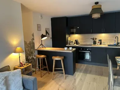 a kitchen with black cabinets and a bar with stools at Appartement de standing 2 chambres, Wi-Fi, animaux admis, parking - FR-1-836-56 in Arâches-la-Frasse