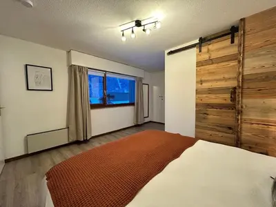 a bedroom with a large bed and a wooden wall at Chalet des Cinq in Samoëns