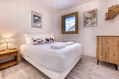 a bedroom with a large white bed and a television at Charmin Savoy - lovely 1 bedroom apartment next to Savoy ski area in Chamonix-Mont-Blanc