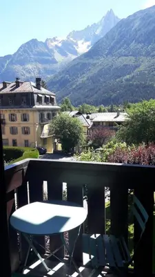 a table and chairs on a balcony with a view of mountains at Charmin Savoy - lovely 1 bedroom apartment next to Savoy ski area in Chamonix-Mont-Blanc