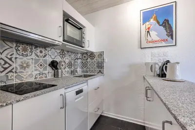 a kitchen with white cabinets and a microwave at Charmin Savoy - lovely 1 bedroom apartment next to Savoy ski area in Chamonix-Mont-Blanc