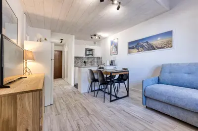 a living room with a blue couch and a table at Charmin Savoy - lovely 1 bedroom apartment next to Savoy ski area in Chamonix-Mont-Blanc