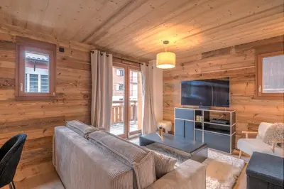 a living room with a couch and a flat screen tv at Appartement Jorat - Welkeys in Megève