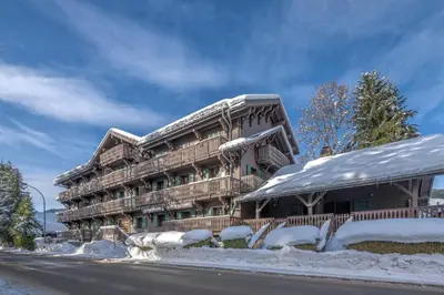 a large wooden building with snow on the ground at Appartement La musardière - Welkeys in Megève