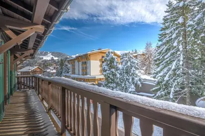 a balcony with snow covered trees and a building at Appartement La musardière - Welkeys in Megève