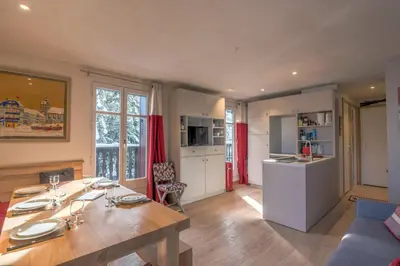 a kitchen and living room with a wooden table and a dining room at Appartement La musardière - Welkeys in Megève