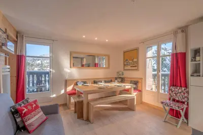 a living room with a wooden table and red curtains at Appartement La musardière - Welkeys in Megève
