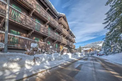 a snow covered road in front of a lodge at Appartement La musardière - Welkeys in Megève