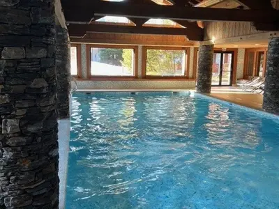 a large swimming pool in a house with a stone wall at Appartement 5 pièces - Piscine et Spa, Capacité 8 pers. - FR-1-836-60 in Arâches-la-Frasse