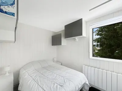 a white bedroom with a bed and a window at OEI30 - 3 pieces 6 pers proche centre station in Les Carroz d'Araches