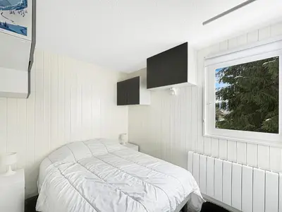 a white bedroom with a bed and a window at OEI30 - 3 pieces 6 pers proche centre station in Les Carroz d'Araches