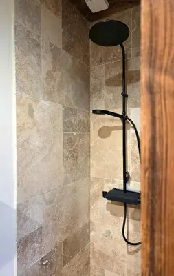 a shower with a black stool in a bathroom at Les Clarines des Contamines in Les Contamines-Montjoie