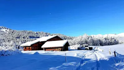 a snow covered cabin with a truck parked next to it at Chalet du Lay Côte 2000 ski in ski out in Megève