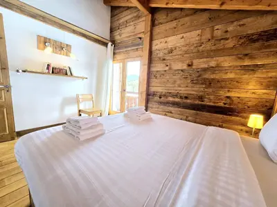 a bedroom with a white bed with wooden walls at Chalet du Lay Côte 2000 ski in ski out in Megève