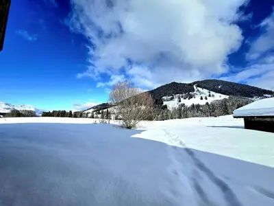 a snow covered field with a mountain in the background at Chalet du Lay Côte 2000 ski in ski out in Megève