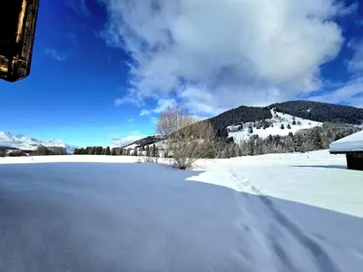 a snow covered field with mountains in the background at Chalet du Lay Côte 2000 ski in ski out in Megève