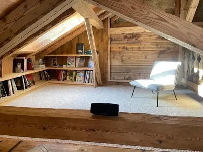 an attic room with a white chair and a book shelf at L'Ultime in Saint-Gervais-les-Bains