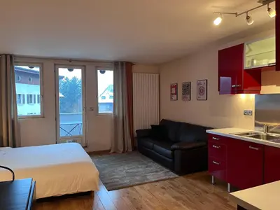 a bedroom with a bed and a couch and a kitchen at Chamonix cœur de ville - Aiguille du midi in Chamonix-Mont-Blanc