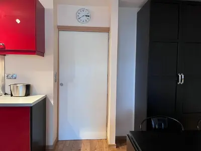 a kitchen with a door with a clock on the wall at Chamonix cœur de ville - Aiguille du midi in Chamonix-Mont-Blanc