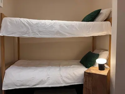 two bunk beds with white sheets and green pillows at Chamonix cœur de ville - Aiguille du midi in Chamonix-Mont-Blanc