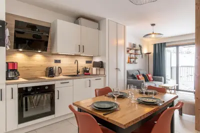 a kitchen and dining room with a wooden table and chairs at Les Ecrins de Kayla -Piscine - Sauna in Les Houches