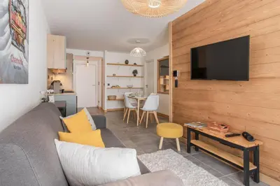 a living room with a couch and a tv on a wall at Kandahar de Kayla - Proche remontée - Espace bien-être in Les Houches