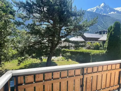 a wooden fence with a tree and a mountain at Spacious 2 bedroom apt with terrace Chamonix center in Chamonix-Mont-Blanc