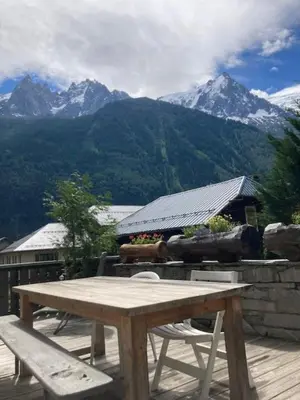 a wooden table and chairs on a deck with mountains at Spacious 2 bedroom apt with terrace Chamonix center in Chamonix-Mont-Blanc