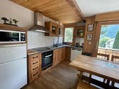 a large kitchen with wooden cabinets and a wooden table at Spacious 2 bedroom apt with terrace Chamonix center in Chamonix-Mont-Blanc