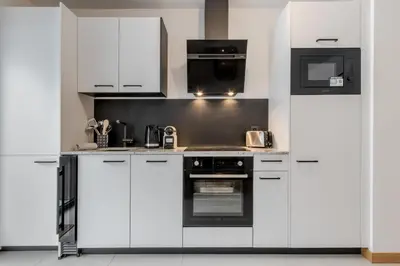 a kitchen with white cabinets and a black oven at Le Manoir de Kayla - Piscine, Sauna & Vue in Les Houches
