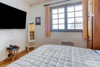a bedroom with a bed and a flat screen tv at L'Etoile de Megève in Megève