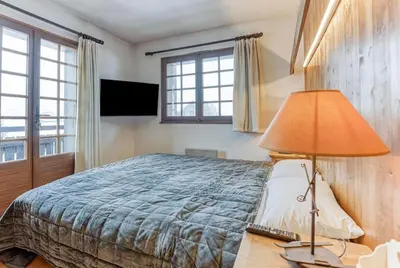 a bedroom with a bed and a lamp on a desk at L'Etoile de Megève in Megève