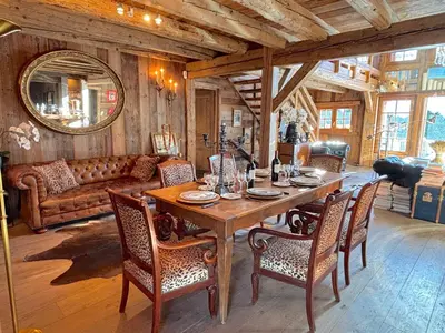 a dining room with a table and chairs and a couch at Chalet Hermine in Megève