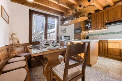 a kitchen with a wooden table and some chairs at Chalet la Chouette - Intimate 2 bedroom demi-chalet ideally located in Chamonix-Mont-Blanc