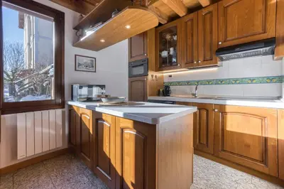 a large kitchen with wooden cabinets and a window at Chalet la Chouette - Intimate 2 bedroom demi-chalet ideally located in Chamonix-Mont-Blanc