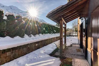 a house in the snow with the sun in the background at Chalet la Chouette - Intimate 2 bedroom demi-chalet ideally located in Chamonix-Mont-Blanc
