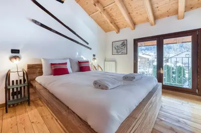 a bedroom with a large white bed with red pillows at Chalet la Chouette - Intimate 2 bedroom demi-chalet ideally located in Chamonix-Mont-Blanc