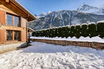 a house in the snow with mountains in the background at Chalet la Chouette - Intimate 2 bedroom demi-chalet ideally located in Chamonix-Mont-Blanc