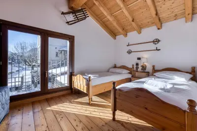 a bedroom with two beds and a large window at Chalet la Chouette - Intimate 2 bedroom demi-chalet ideally located in Chamonix-Mont-Blanc