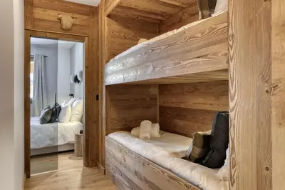 a bedroom with two bunk beds and a mirror at L'Alezan I Appartement proche du centre de Megève in Megève