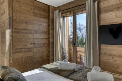 a bedroom with wooden walls and a bed with two towels at L'Alezan I Appartement proche du centre de Megève in Megève