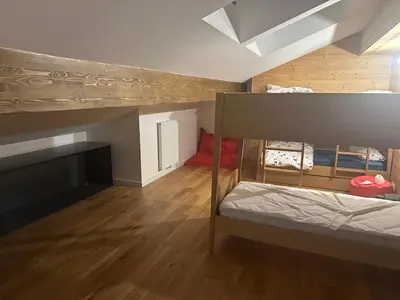 a small room with a bunk bed and wooden floors at L'écrin de Samoëns in Samoëns