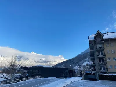 a snow covered city with a building and mountains at Appartement pour 6 personnes au pied du téléphérique in Saint-Gervais-les-Bains