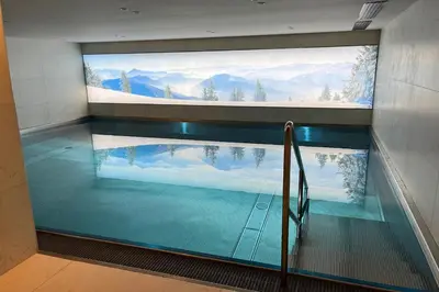 a swimming pool with a large window in a building at Appartement Montalis - Welkeys in Megève