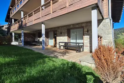 a wooden deck with a bench on the side of a building at Appartement Montalis - Welkeys in Megève