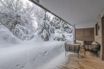 a snowy porch with two chairs and a table at Appartement Montalis - Welkeys in Megève