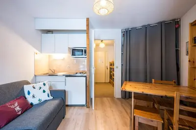 a living room with a couch and a table and a kitchen at Le Cocon des Pistes - Station à 10 minutes in Les Contamines-Montjoie