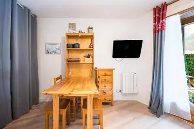 a dining room with a table and a tv at Le Cocon des Pistes - Station à 10 minutes in Les Contamines-Montjoie