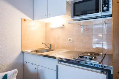 a small kitchen with a sink and a microwave at Le Cocon des Pistes - Station à 10 minutes in Les Contamines-Montjoie